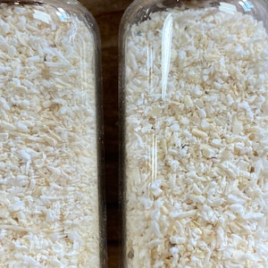 May include: Two clear glass jars filled with white, dried, shredded coconut flakes.