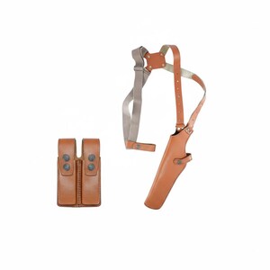 May include: A light brown leather shoulder holster with a matching double magazine pouch. The holster features adjustable straps and metal hardware. The magazine pouch has two compartments with snap closures. The set is designed for carrying a firearm and ammunition.