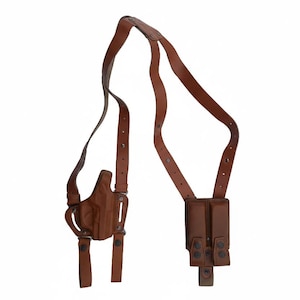 May include: A brown leather shoulder holster with a matching magazine pouch. The holster has adjustable straps and a molded design to securely hold a firearm. The magazine pouch has two compartments and snap closures.