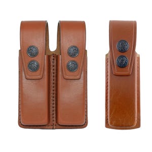 May include: Two brown leather holsters with metal snaps. One holster is double-sided and the other is single-sided.