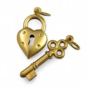 May include: A gold heart-shaped padlock charm with a keyhole and a matching gold key charm with a decorative design. The charms are perfect for adding a touch of romance to jewelry or crafts.