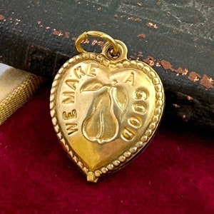 May include: A gold heart-shaped charm with the words "We make a good" and a pear design.
