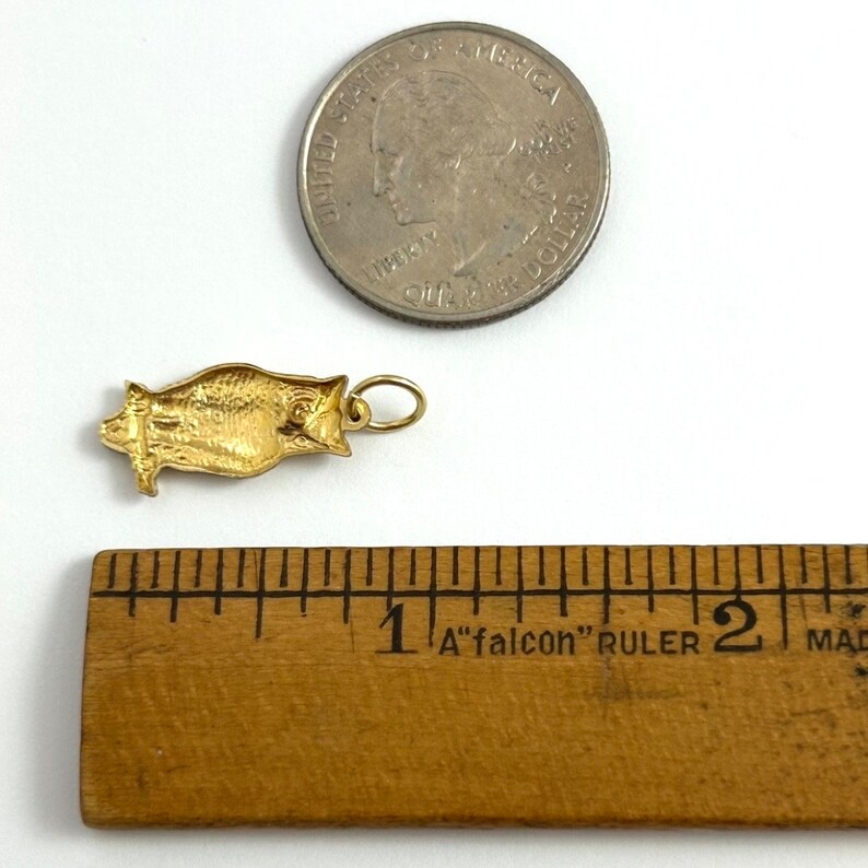 May include: Gold owl charm pendant, approximately 1 inch in length, next to a US quarter for size comparison.