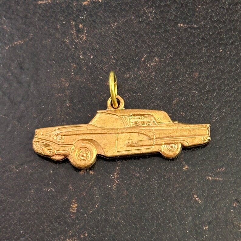 Puede incluir: Un dije de metal dorado en forma de coche antiguo. El dije tiene un dise&ntilde;o detallado y es perfecto para agregar un toque de nostalgia a un collar o pulsera.