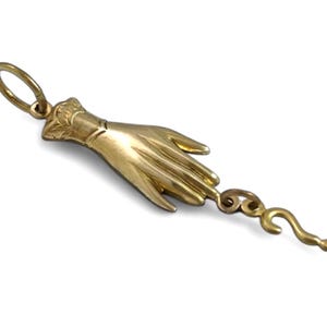 K&ouml;nnte beinhalten: Ein goldener Anh&auml;nger in Form einer Hand mit einem Fragezeichen am Finger.