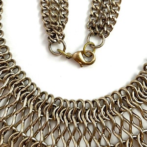 May include: A silver metal necklace with a chain link design. The necklace has a clasp closure.