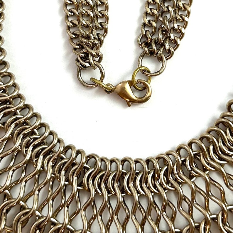 May include: A silver metal necklace with a chain link design. The necklace has a clasp closure.