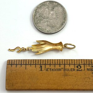K&ouml;nnte beinhalten: Goldener Anh&auml;nger in Form einer Hand mit einem kleinen Fragezeichen-Anh&auml;nger. Der Anh&auml;nger ist etwa 2,5 cm lang.