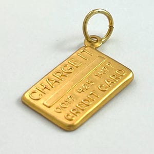 May include: Gold-coloured charm shaped like a credit card with the text "CHARGE IT" and "CREDIT CARD" and the number "0017 428 1477".