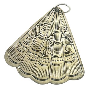 Puede incluir: Colgante plateado en forma de abanico con intrincados patrones grabados. El colgante presenta un borde festoneado y un peque&ntilde;o anillo en la parte superior para sujetarlo. El dise&ntilde;o incluye l&iacute;neas verticales y detalles en espiral, creando una est&eacute;tica vintage.