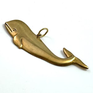 May include: A gold-coloured whale charm with a loop for attaching to a necklace or bracelet.