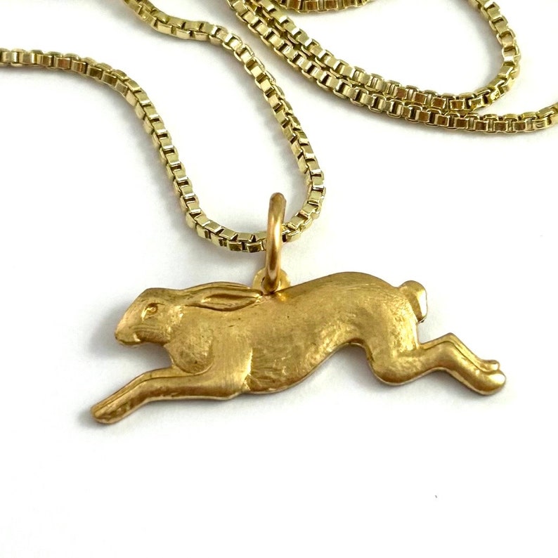 May include: A gold chain necklace with a gold pendant shaped like a running hare.