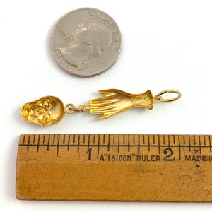 Op de afbeelding: Goudkleurige hanger met een schedel en een hand. De hanger is ongeveer 2,5 cm lang.