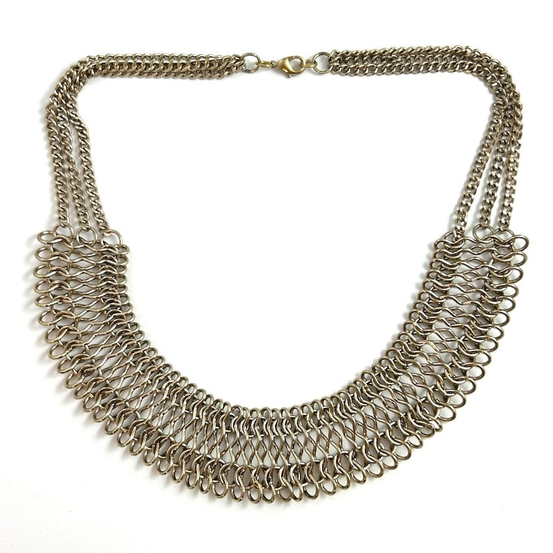 May include: A gold-toned chain necklace with a layered, woven design. The necklace has a clasp closure.