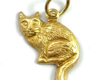 May include: A gold-colored charm in the shape of a sitting cat. The charm has a loop at the top for attaching to a necklace or bracelet.