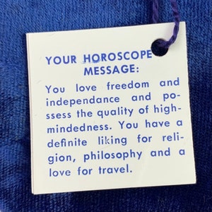 May include: A white card with blue text that reads "YOUR HOROSCOPE MESSAGE: You love freedom and independence and possess the quality of high-mindedness. You have a definite liking for religion, philosophy and a love for travel."