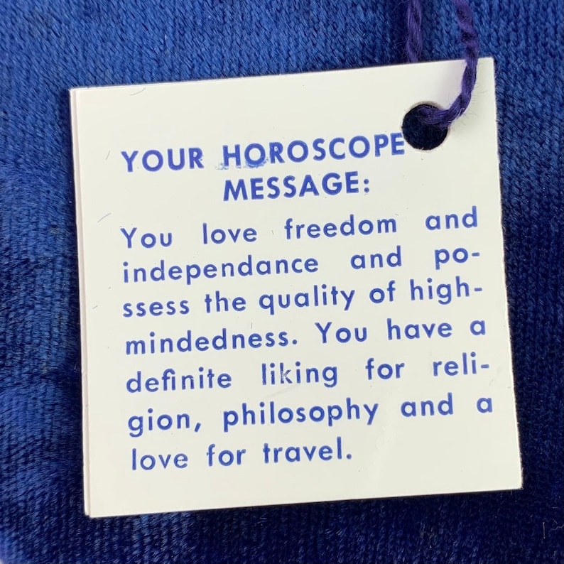 May include: A white card with blue text that reads "YOUR HOROSCOPE MESSAGE: You love freedom and independence and possess the quality of high-mindedness. You have a definite liking for religion, philosophy and a love for travel."
