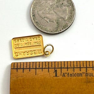 May include: Gold-toned charm shaped like a credit card with the text "CREDIT CARD" and "CHANCE III" on it. The charm is approximately 2.5 cm long and is next to a ruler for size reference.