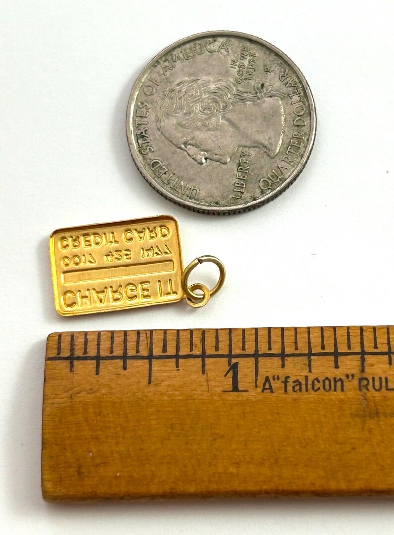 May include: Gold-toned charm shaped like a credit card with the text "CREDIT CARD" and "CHANCE III" on it. The charm is approximately 2.5 cm long and is next to a ruler for size reference.
