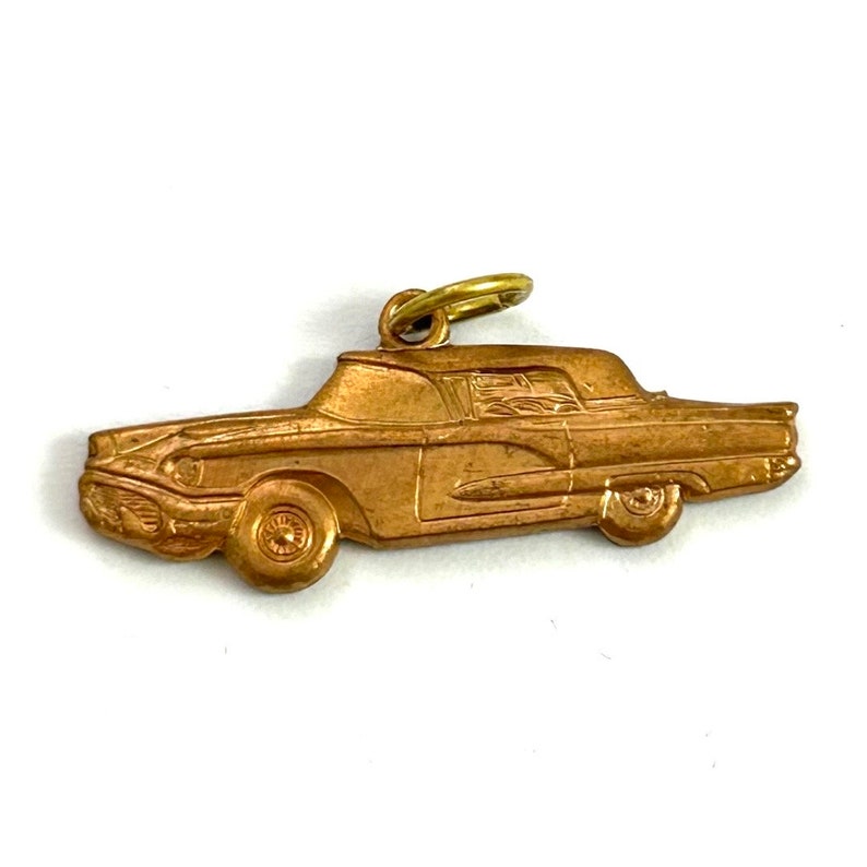 Puede incluir: Un dije de metal dorado en forma de coche antiguo. El dije tiene un dise&ntilde;o detallado y un bucle en la parte superior para sujetarlo a un collar o pulsera.