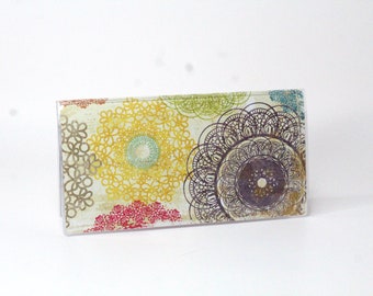 May include: A clear plastic wallet with a colorful floral pattern. The pattern features yellow, red, green, and purple flowers with intricate details.
