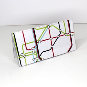 May include: A white card with a black, red, green, and blue subway map design. The card is folded in half and standing upright.