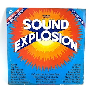 May include: A square vinyl record album cover titled Sound Explosion. The design features a large orange and yellow sunburst graphic on a blue background. Text includes 20 Original Hits By Original Artists, Ronco Presents, and As Seen On T.V., along with a list of various musical artists printed in black.