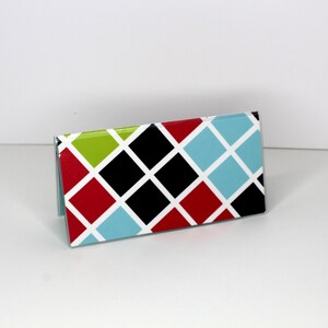 May include: A folded card with a geometric pattern of red, black, green, and blue diamonds on a white background.