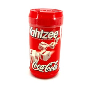 May include: A red Yahtzee game container with the Coca-Cola logo and dice. The container is cylindrical and features the game's name and the phrase "The Classic Shake and Score Dice Game". The dice have Coca-Cola branding.