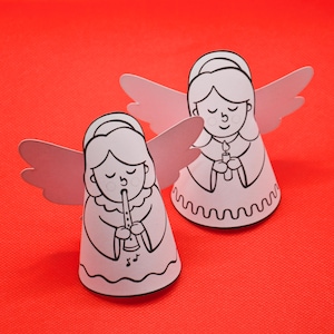 May include: Two white paper angel ornaments with black outlines. One angel is playing a flute and the other is holding a candle. Both angels have closed eyes and are wearing a simple dress.