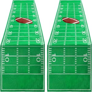 May include: Two green table runners with a football field design. Each runner features yard lines, numbers, and a brown football graphic. The runners are perfect for a football-themed party or home decor.