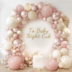 May include: A balloon arch in shades of pink, cream, and pearl, arranged in a semi-circle. The arch is decorated with small white flowers and the text "To Baby Night Cub". A white square block is at the base of the arch.