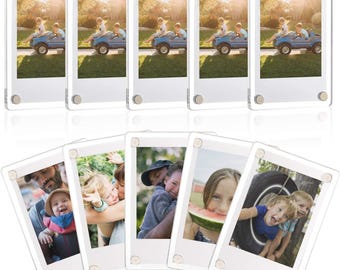 May include: A set of ten clear acrylic magnetic photo frames, each featuring four silver-toned metal corner fasteners. These rectangular frames are designed to hold photographs securely between two transparent panels for a floating display effect.