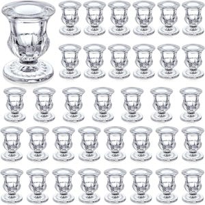 May include: A collection of clear glass candle holders. The candle holders have a round base, a decorative stem, and a circular top to hold a candle. The glass has a textured, faceted design. The image shows a variety of these candle holders.