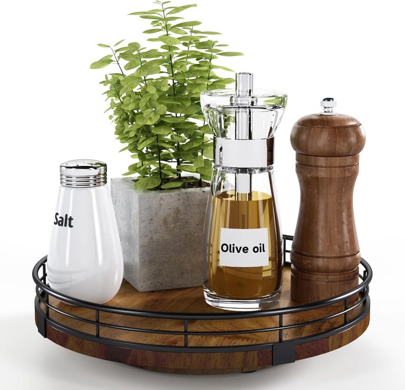May include: A round wooden serving tray with a black metal rim. The tray has a salt shaker, an olive oil dispenser, a pepper grinder, and a small potted plant on it.