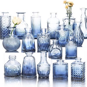 May include: A collection of seventeen small glass vases in varying shades of blue, featuring diverse textures including diamond patterns, vertical ribs, and smooth surfaces. Some vases are clear, while others exhibit a blue gradient finish.