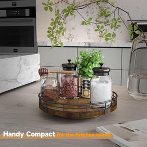 May include: A wooden rotating serving tray with a black metal frame. The tray is filled with glass jars containing spices and a small potted plant. The tray is on a light brown countertop.
