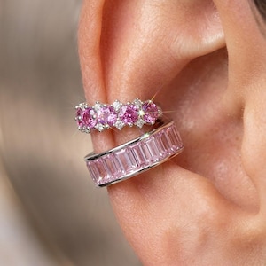 May include: A silver ear cuff set consisting of two pieces. The top piece features a row of round, vibrant pink stones accented by small clear stones. The bottom piece is a wider band set with a continuous row of rectangular, light pink stones.