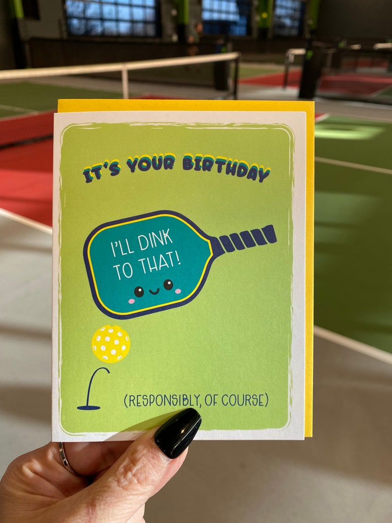 May include: A yellow and green birthday card with a cartoon pickleball paddle and the text "It's your birthday. I'll Dink to that! (Responsibly, of course)"