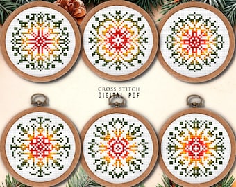 May include: Six round cross stitch patterns featuring a colorful snowflake design in shades of red, orange, yellow, and green. The patterns are framed in wooden hoops.