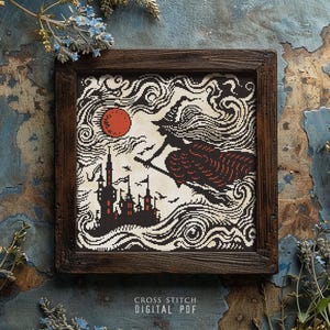 Könnte beinhalten: Ein Kreuzstichmuster mit einer Hexe, die auf einem Besen mit einem Schloss im Hintergrund fliegt. Das Muster ist in einem Holzrahmen und hat einen roten Mond und wirbelnde Wolken.