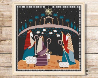 Peut inclure: Modèle de point de croix représentant une scène de la Nativité avec trois personnages, une étoile et des moutons. Les personnages sont vêtus de rouge, de bleu et de vert. L'arrière-plan est noir avec des étoiles blanches.