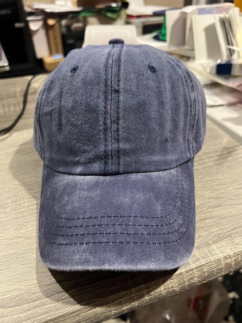 May include: A dark blue denim baseball cap with a slightly distressed look. The cap has a curved brim and a structured crown.