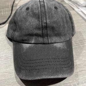 May include: A black denim baseball cap with a slightly distressed look. The cap has a curved brim and a structured crown.