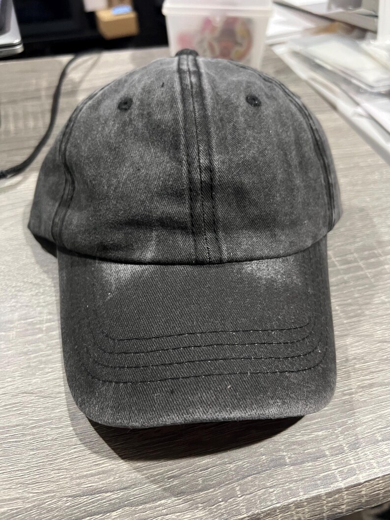 May include: A black denim baseball cap with a slightly distressed look. The cap has a curved brim and a structured crown.