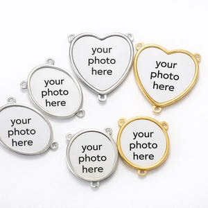 May include: A collection of metal photo charms in various shapes: oval, heart, and round. Each charm has a white center with the text "your photo here" in black. Some charms have silver-colored frames, while others are gold-colored.