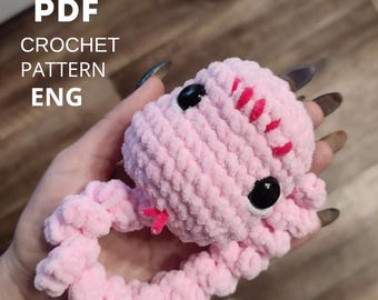 May include: A handmade pink crochet snake toy with black eyes and red accents. The plush toy is held in a hand. Text on the image reads "PDF CROCHET PATTERN ENG".