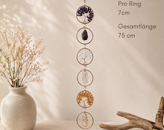 Könnte beinhalten: Ein vertikaler Hängeschmuck mit sechs kupferfarbenen Ringen, die durch eine Kette verbunden sind. Die Ringe enthalten drahtgewickelte Baumdesigns mit violetten, klaren und gelben Kristallen, abwechselnd mit dunklen Rohsteinen. Text: Pro Ring 7cm, Gesamtlänge 75 cm.