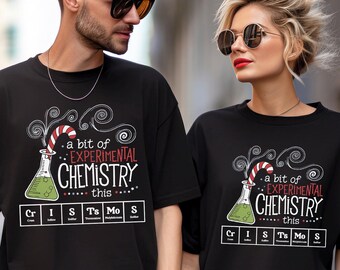 May include: Black t-shirts with the text "a bit of EXPERIMENTAL CHEMISTRY this" and a beaker design. The design includes the periodic table elements Cr, I, Ts, Mo, and S. The shirts are worn by two people.
