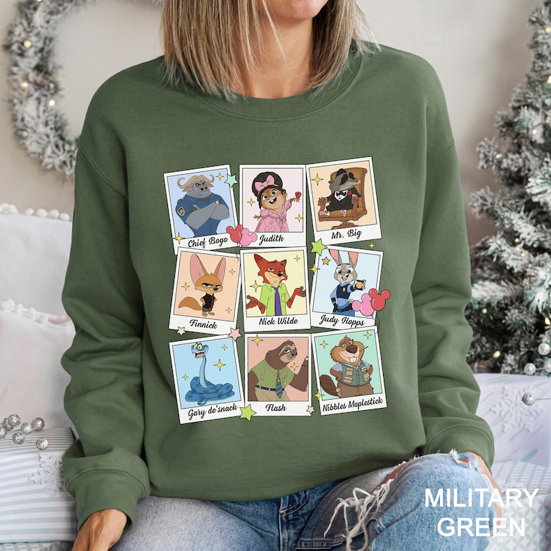 May include: A military green sweatshirt with a grid of cartoon character portraits. Each portrait is framed and labelled with names such as "Chief Bogo," "Judy Hopps," and "Nick Wilde." The text "MILITARY GREEN" is printed at the bottom right.